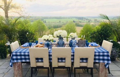 Gedekte tuintafel met blauw wit geruit tafelkleed en servetten met uitzicht over het landschap - Bamar Lifestyle