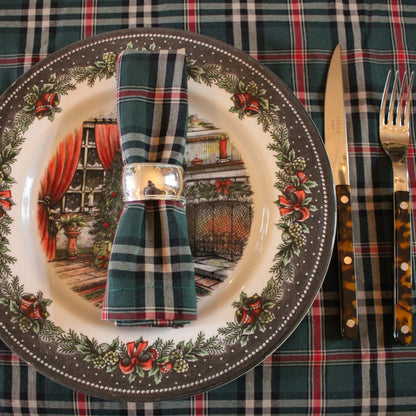 Bovenaanzicht van gedekte tafel met Schotse ruit tafelkleed en servetten. Het Castle groen servet is op een bord gedecoreerd met zilveren servetring. 