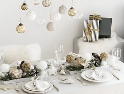 Gedekte tafel met kerstballen met wit tafelkleed en servetten